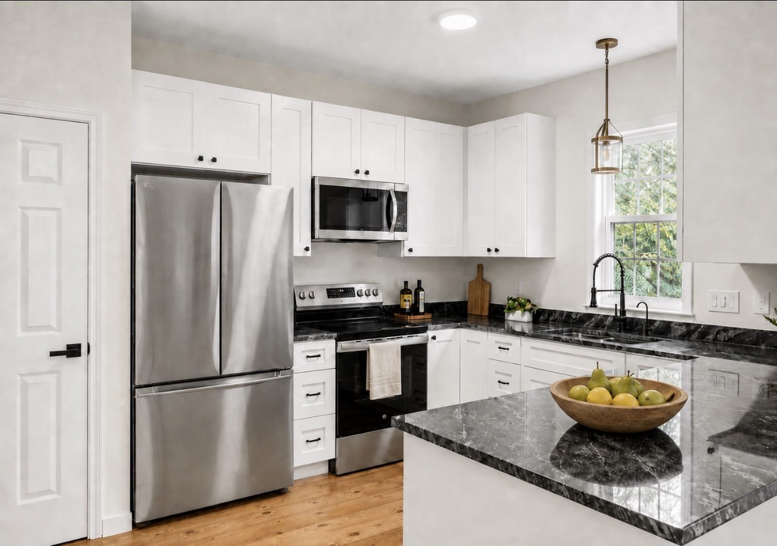 Remodeled kitchen with white cabinets, stainless steel appliances, and dark stone countertops